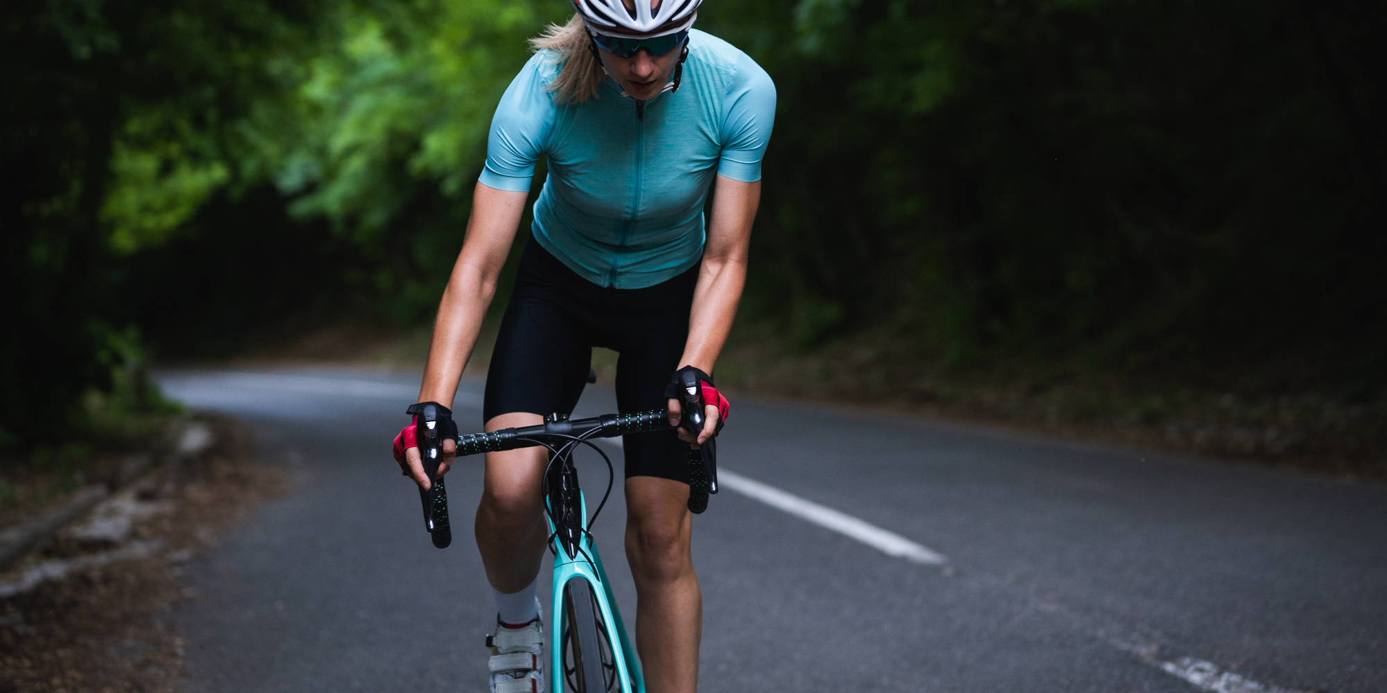 Frau fährt auf einem Rennrad einen Berg hinauf.