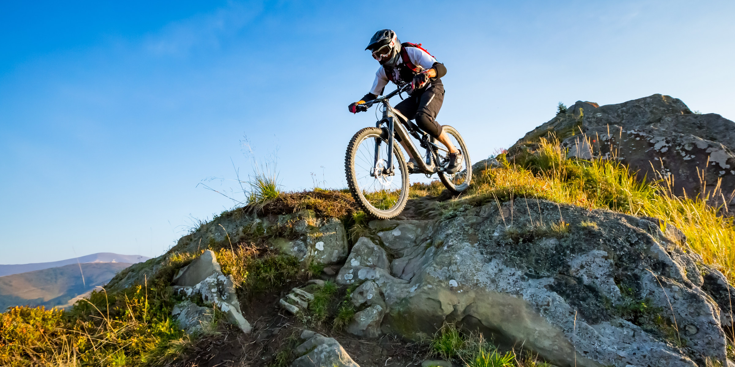 Ein Mann fährt auf einem Mountainbike eine Downhill Strecke auf einem Berg