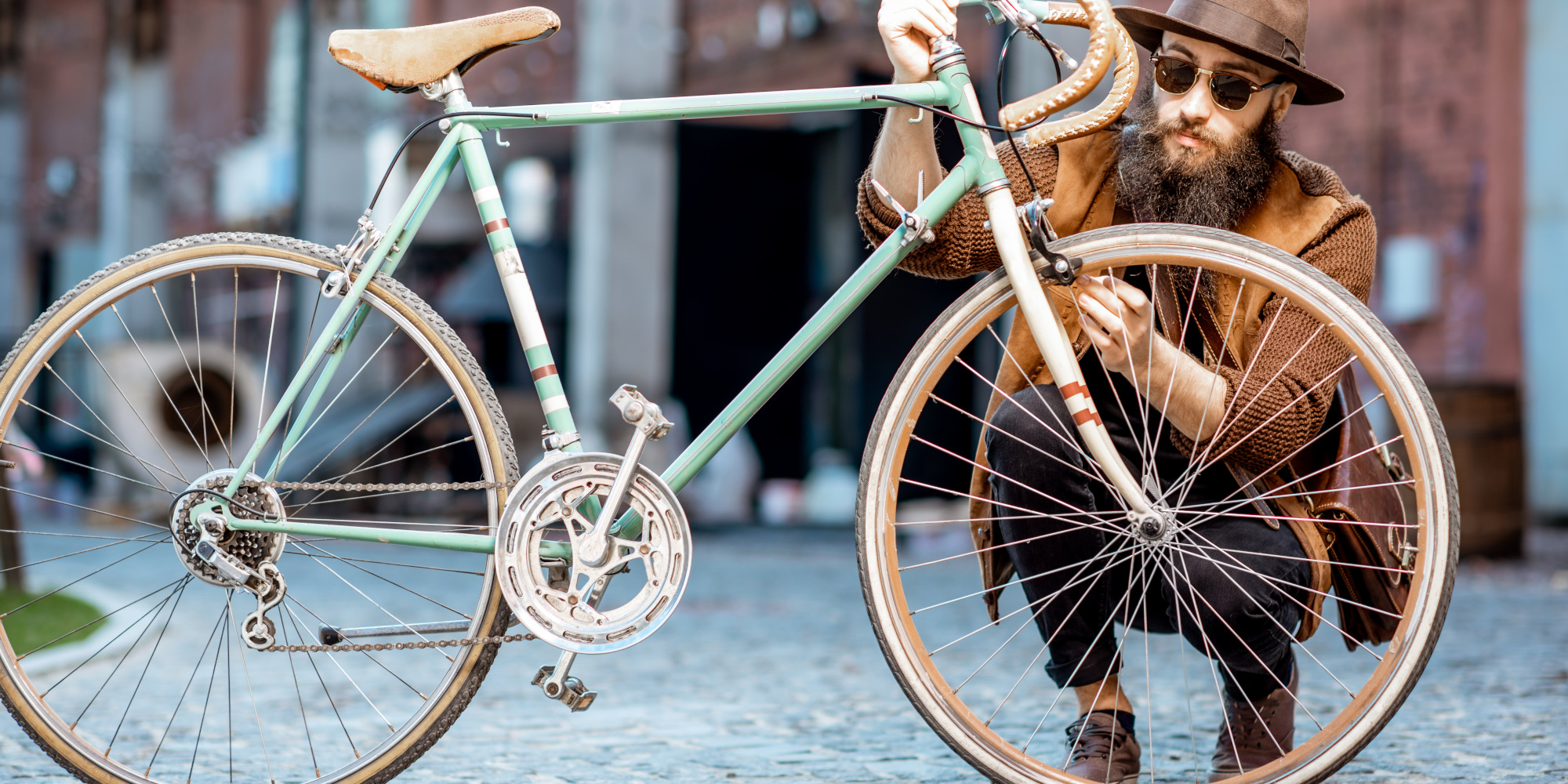 Mann kniet hinter einem Retro Fahrrad.