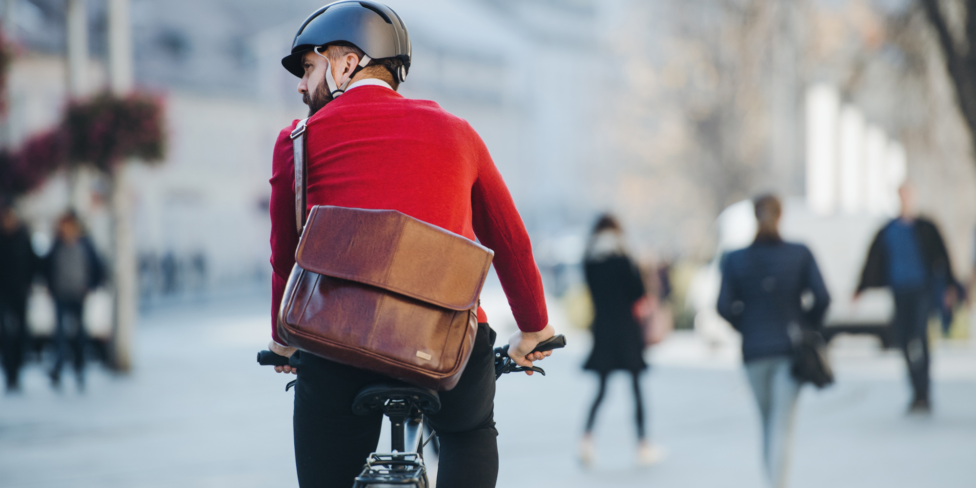 Mann fährt mit einer Arbeitstasche auf einem Fahrrad durch die Stadt.