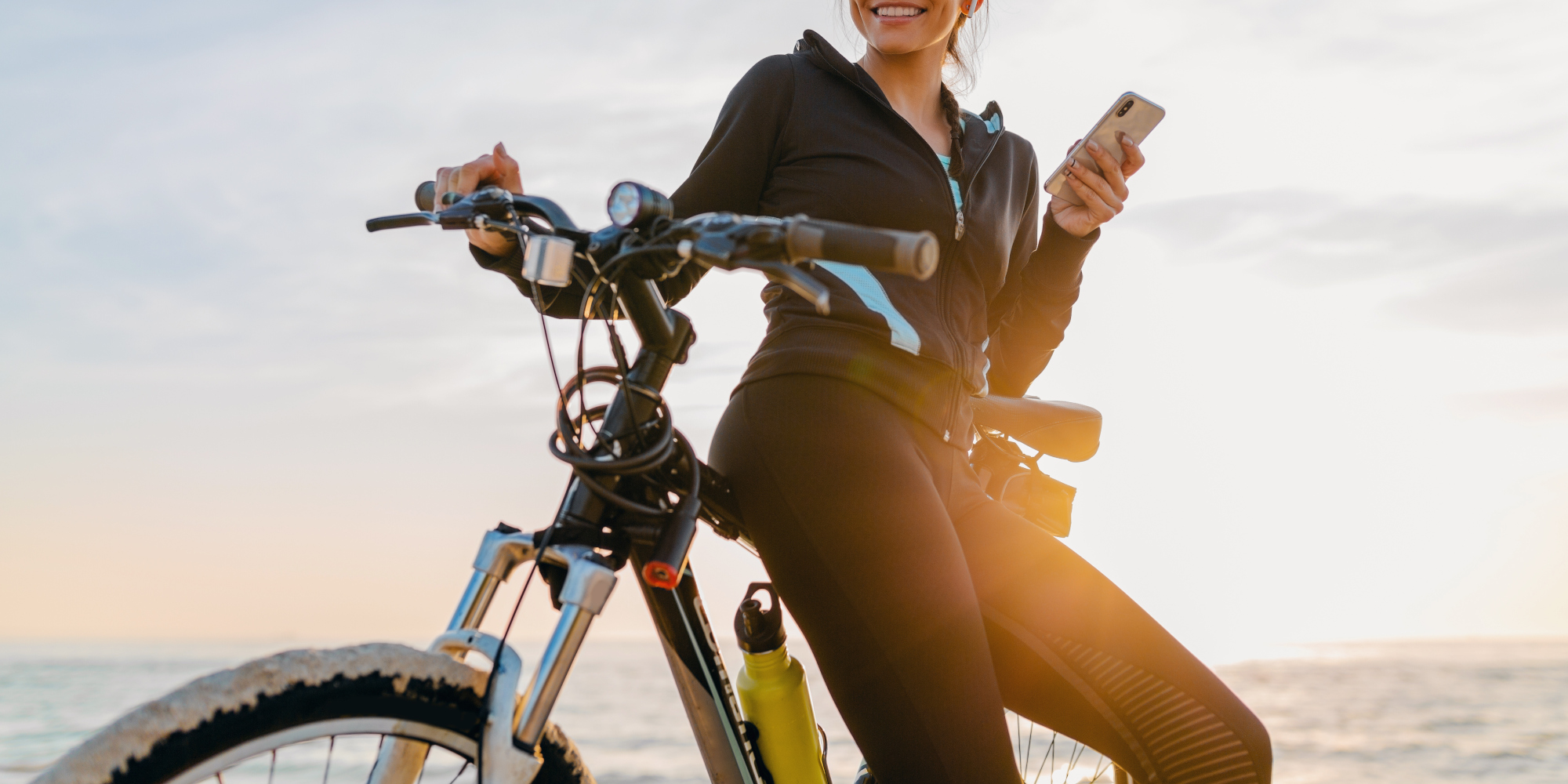 Frau lehnt an einem Fahrrad und schaut auf ihr Handy