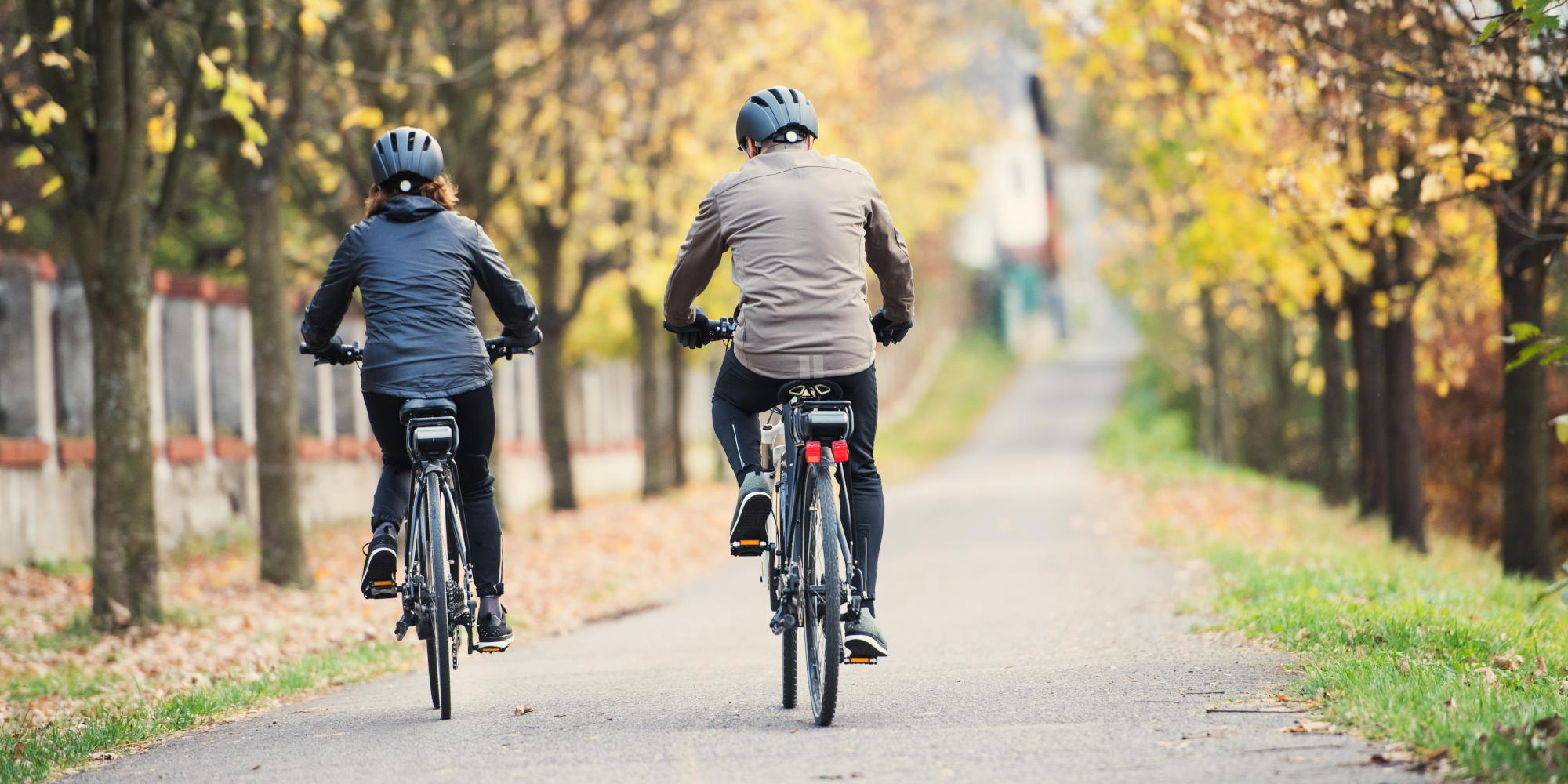 Mann und Frau fahren im Herbst mit E-Bike.