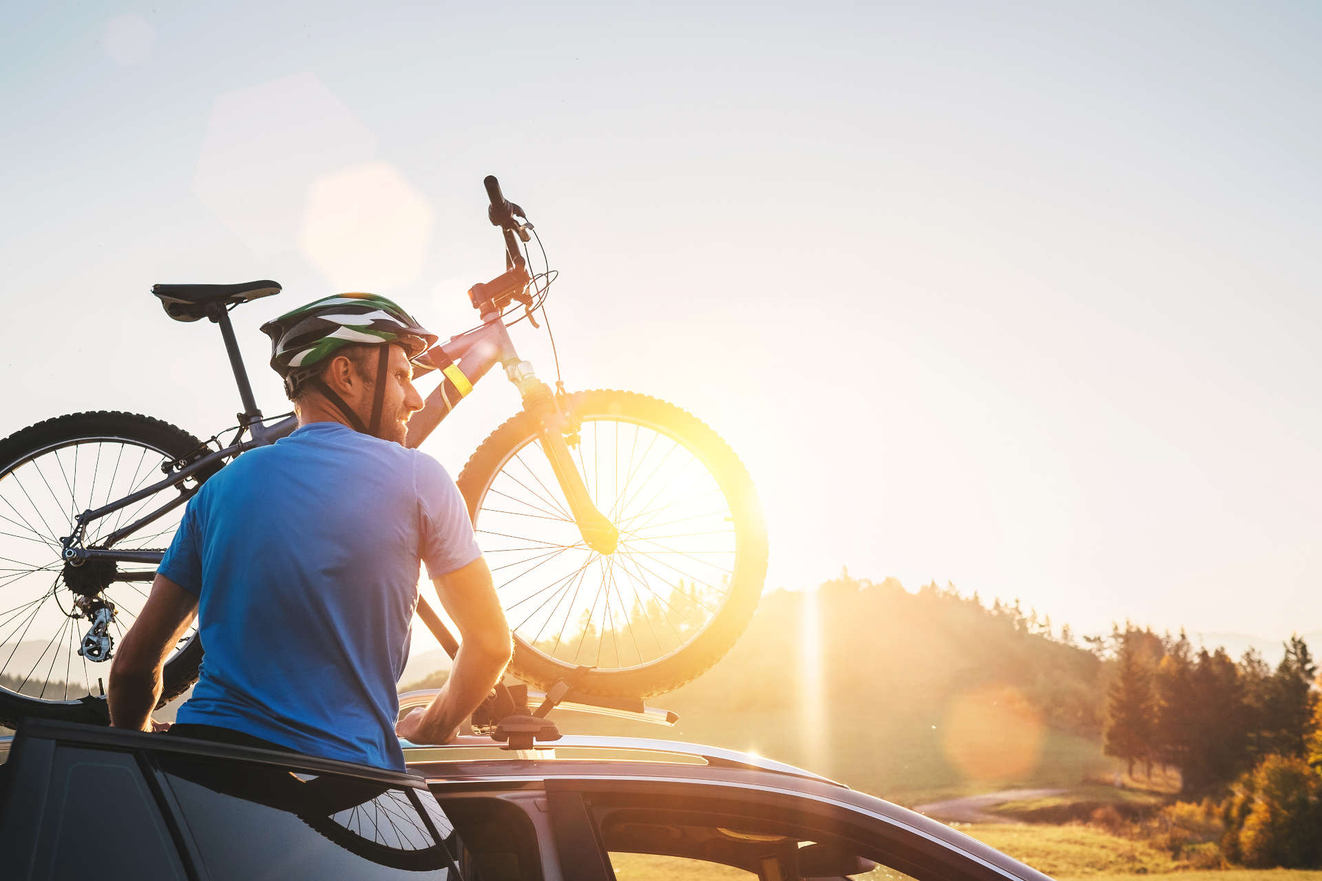 Person befestigt ein Fahrrad auf dem Fahrradträger für das Dach.