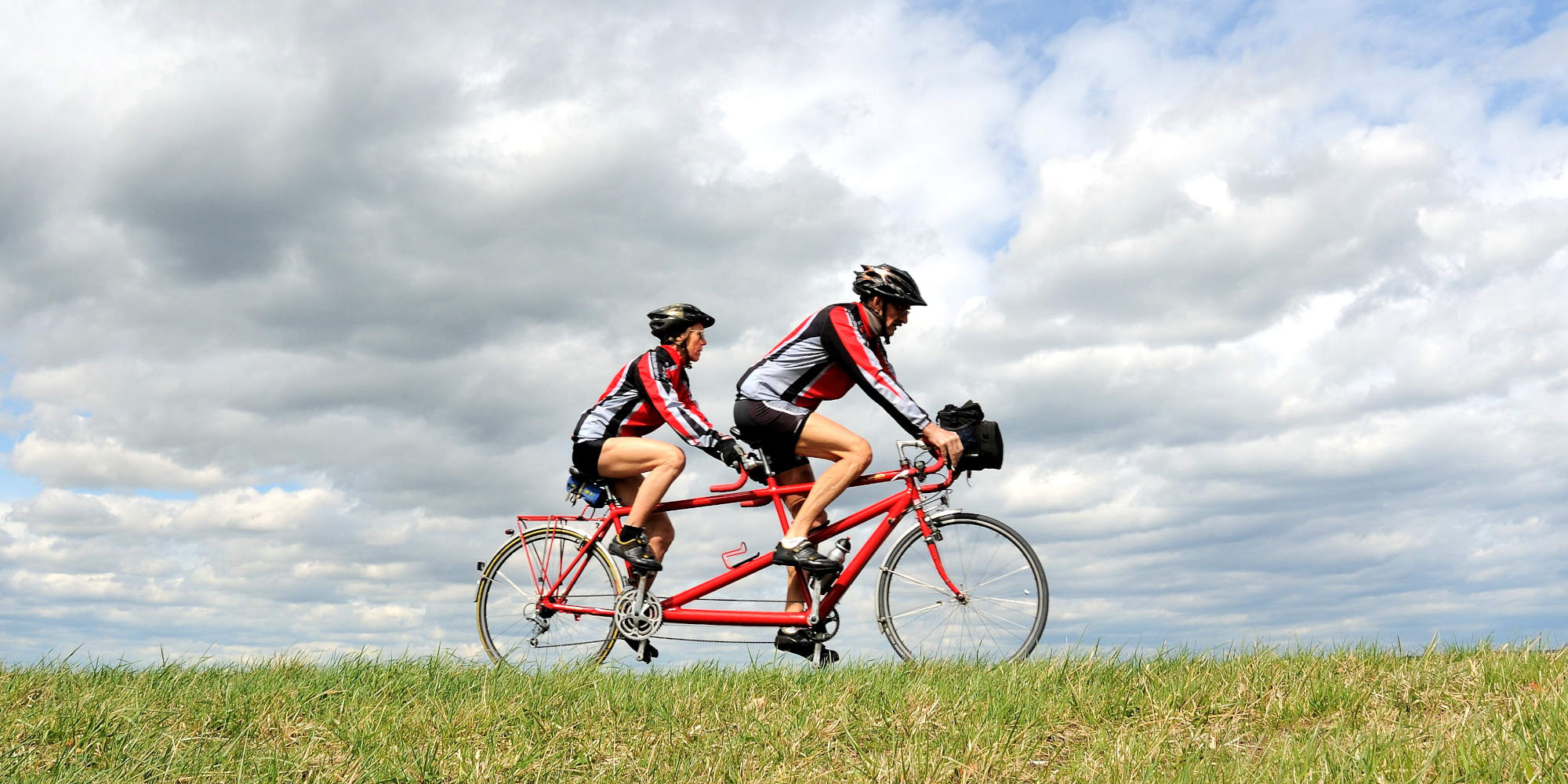 Mann und Frau fahren mit Tandem über Wiese.