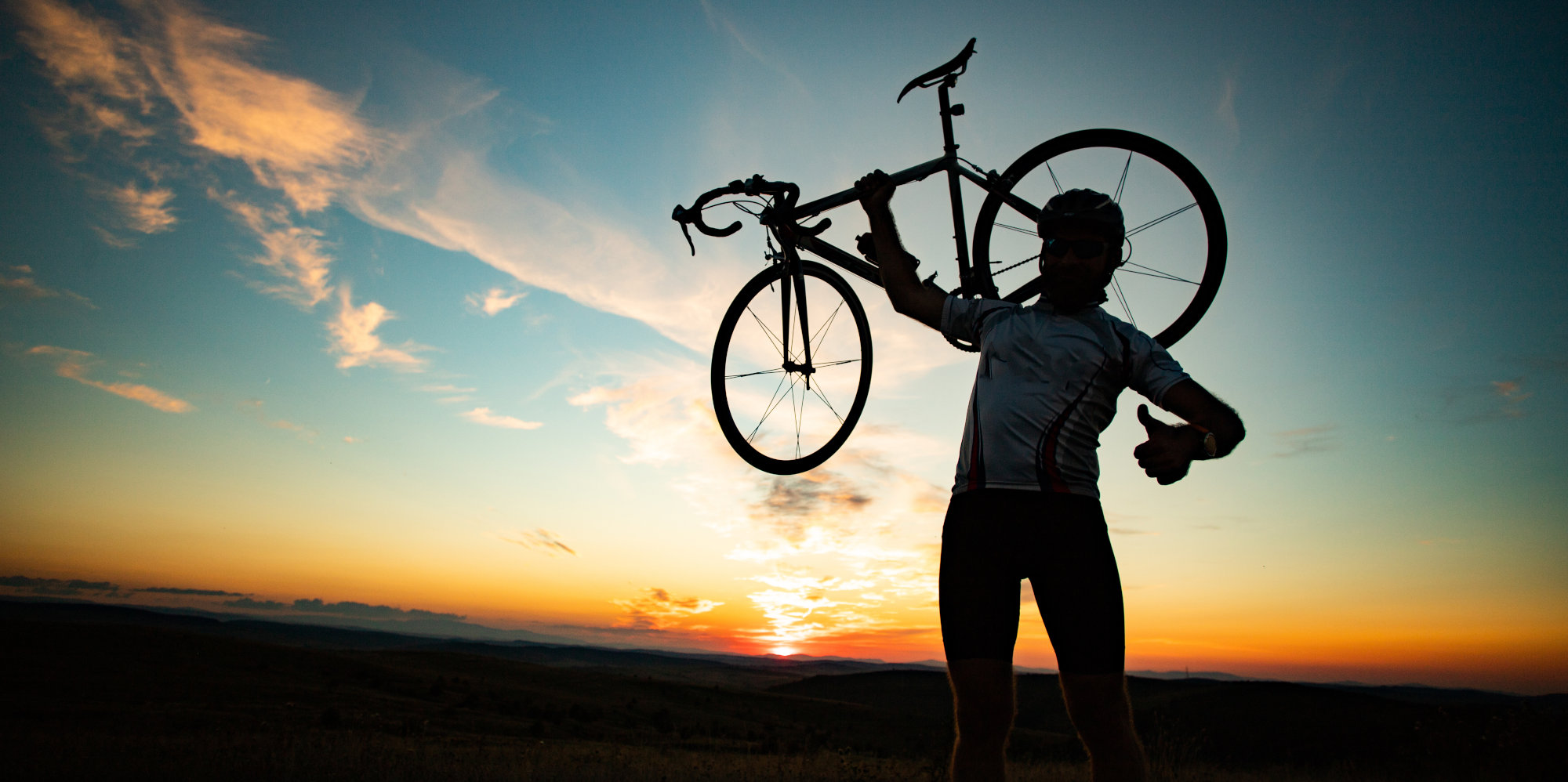 Mann hält Fahrrad hoch und zeigt Daumen nach oben.