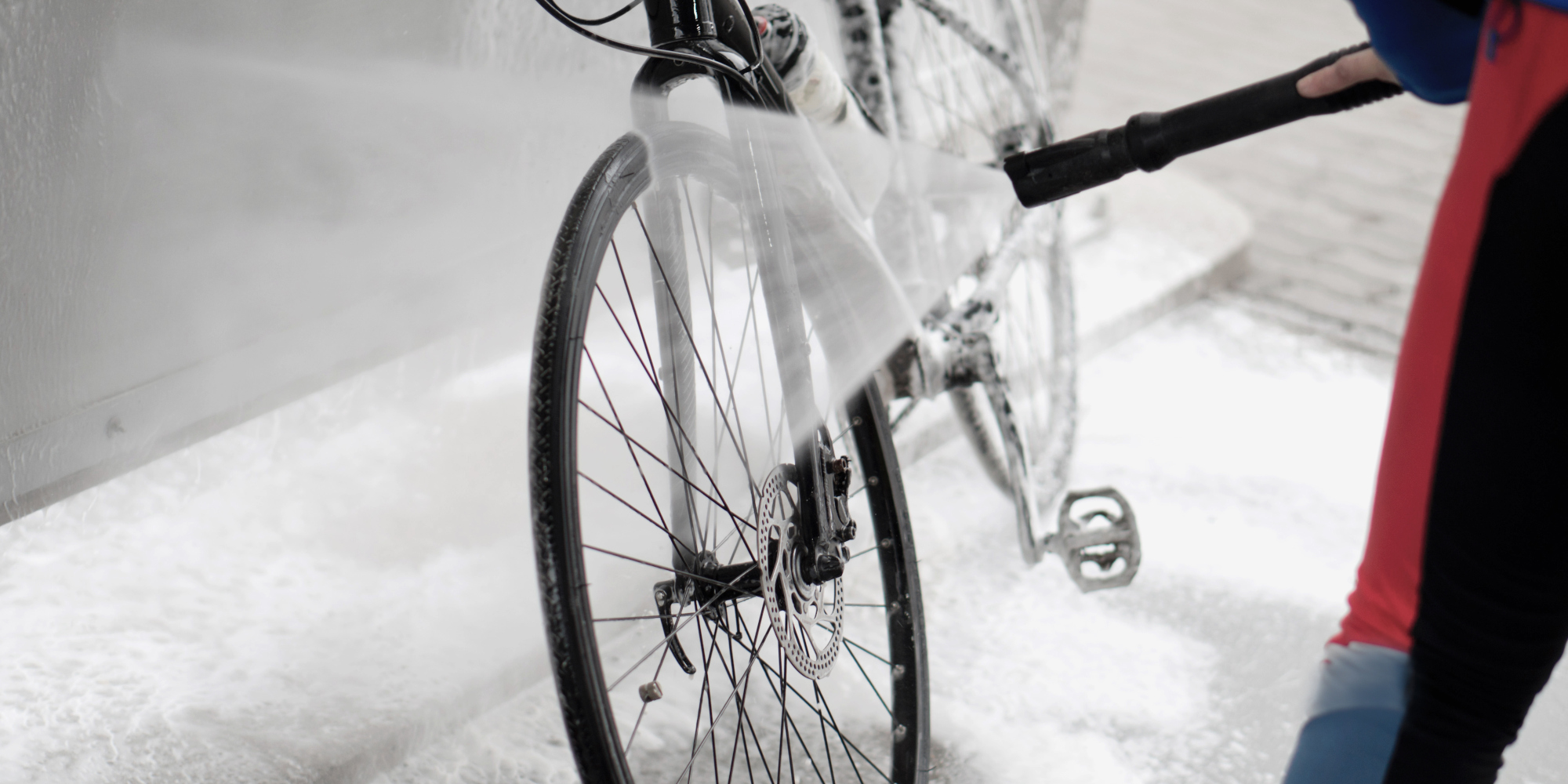 Mann reinigt ein Fahrrad mit einem Hochdruckreiniger