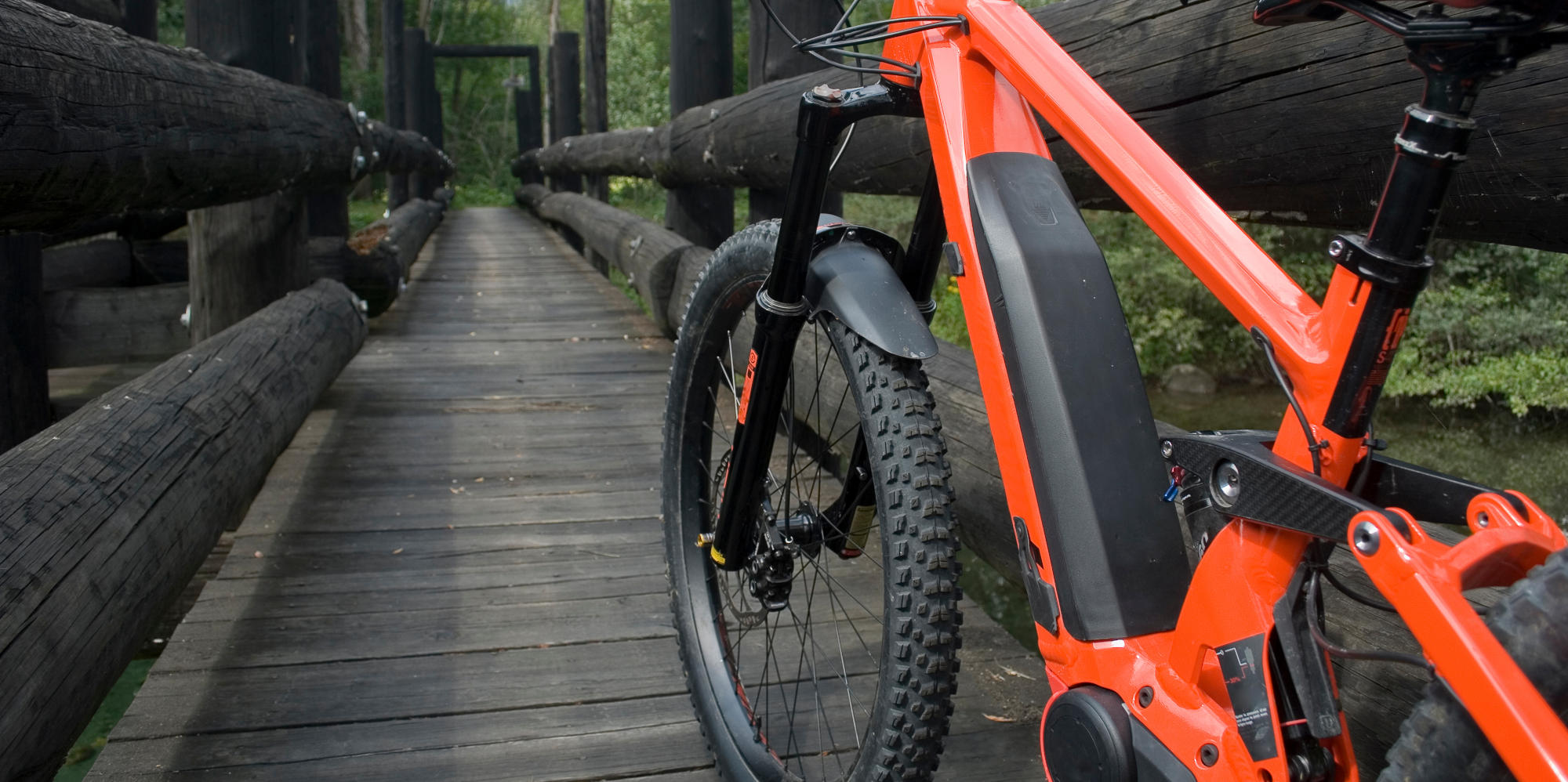 Foto von rotem E-Mountainbike auf Brücke im Wald.