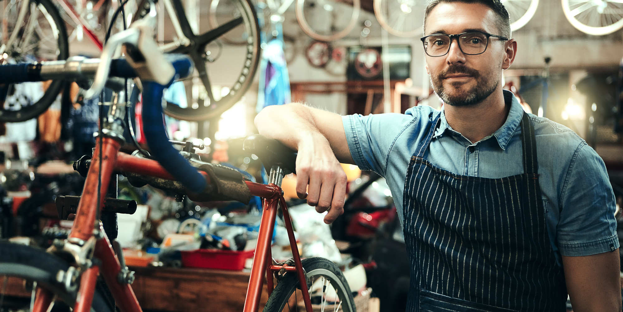 Fahrrad-Mechaniker steht neben einer Werkbank mit Fahrrad.