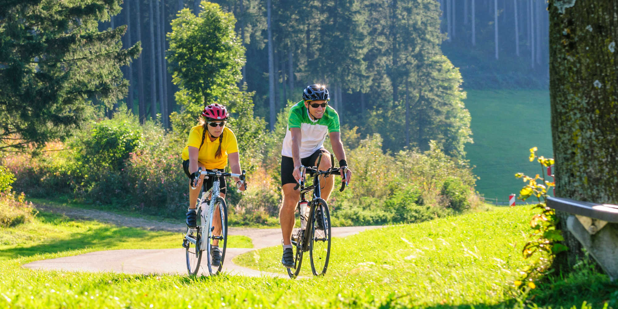 Mann und Frau mit Rennrad fahren See entlang.