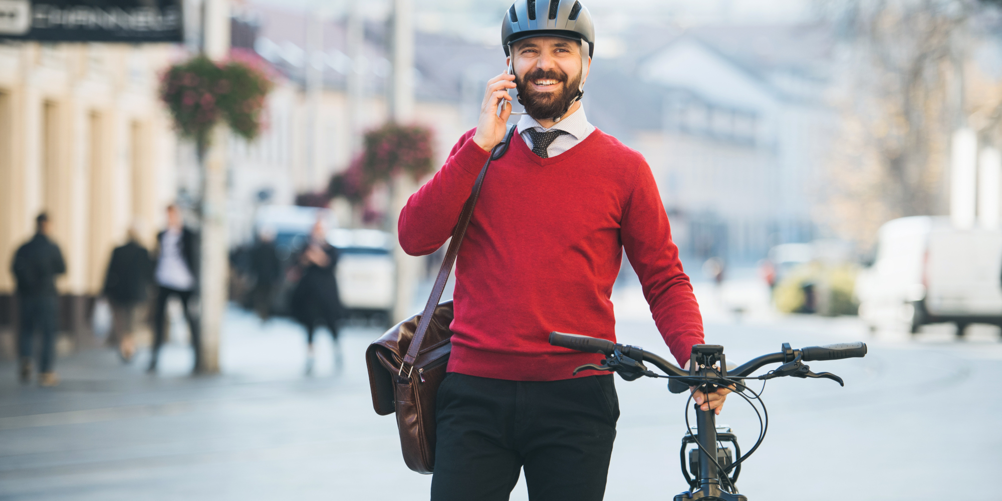 Mann telefoniert und hält ein Fahrrad an der Hand 