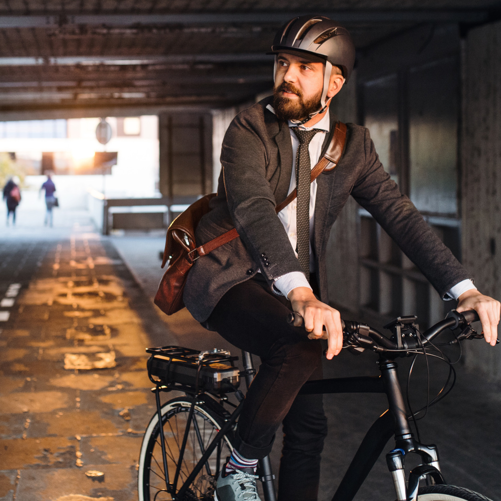 Mann in Business-Klamotten fährt mit einem E-Bike durch einen Tunnel.