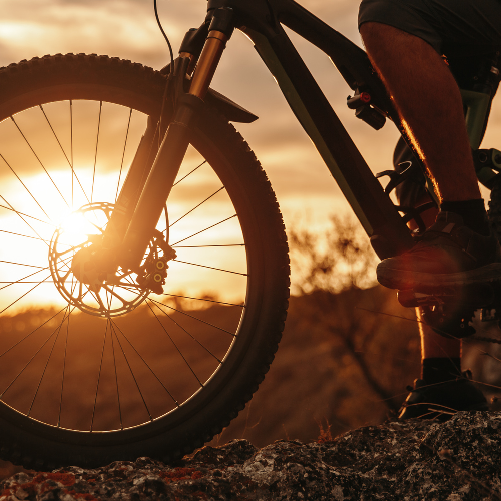 Mann fährt mit einem Fahrrad über einen Felden im Sonnenuntergang