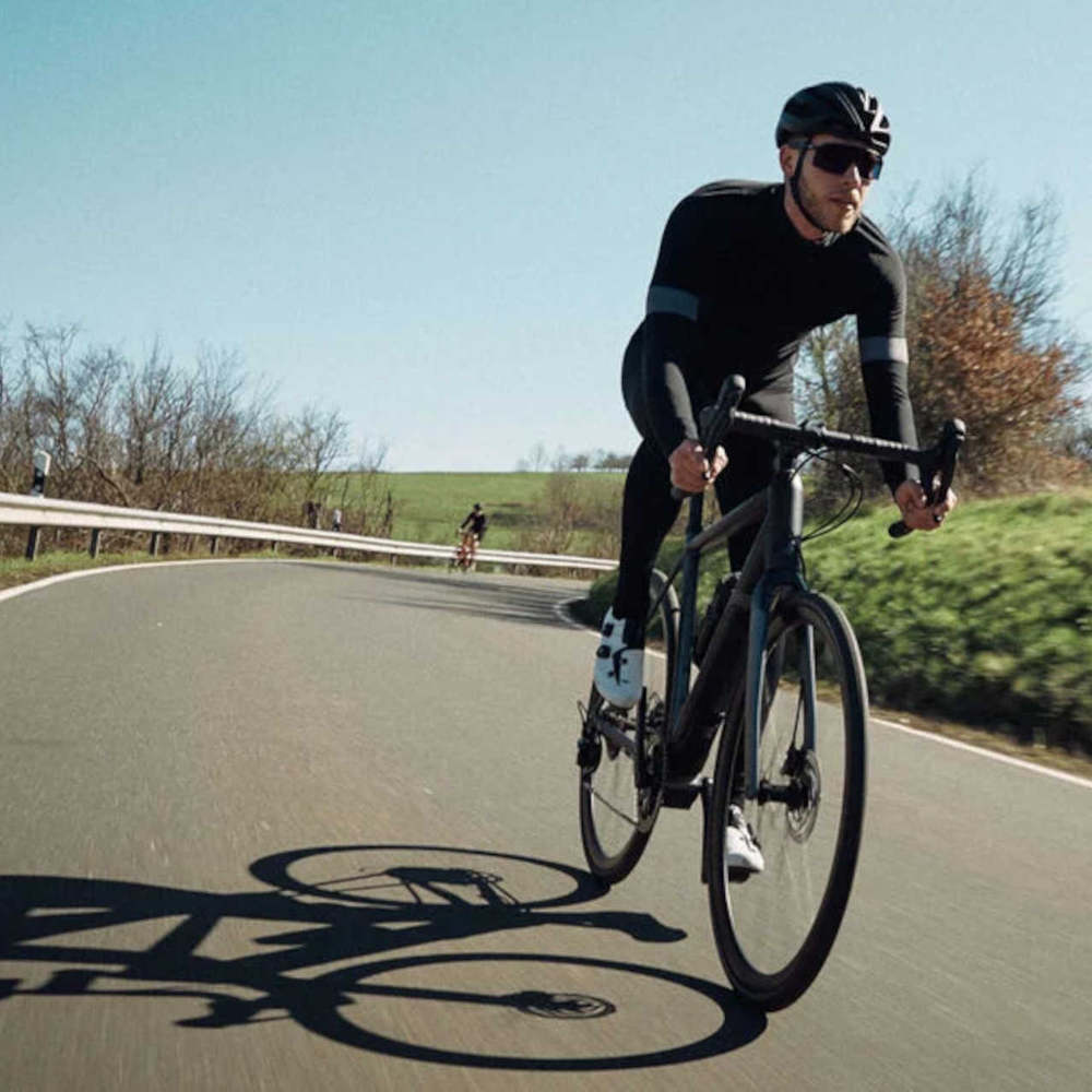 Mann fährt auf Rennrad über Strasse.