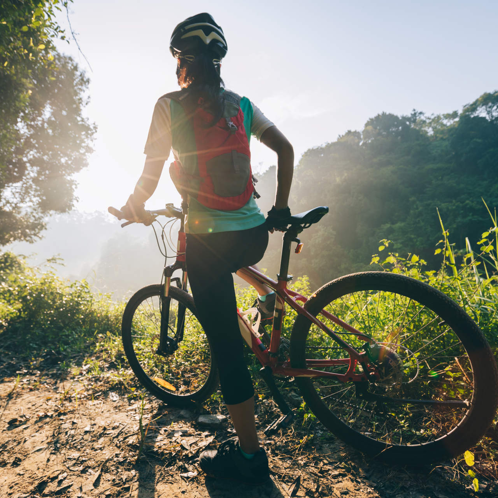 Person steht mit ihrem Mountainbike im Wald