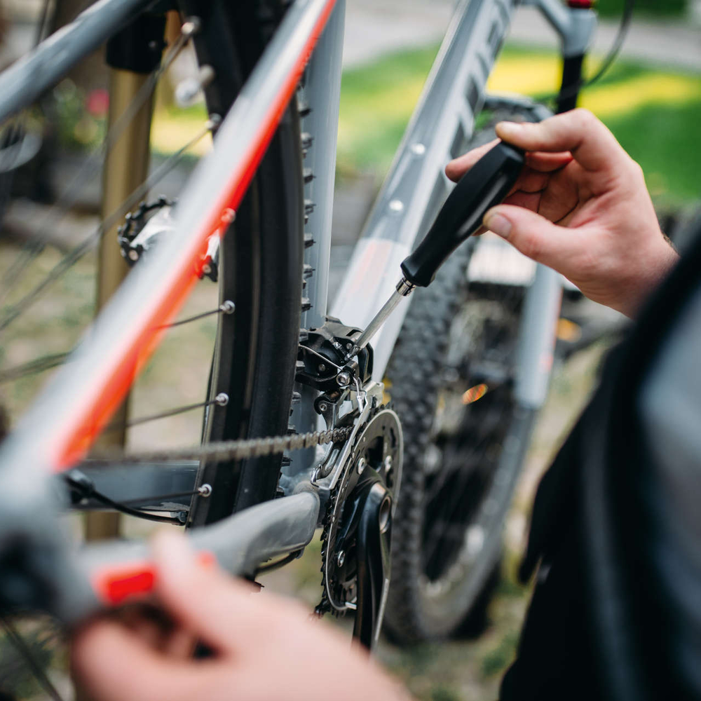 Mann schraubt an der Schaltung von einem Fahrrad.