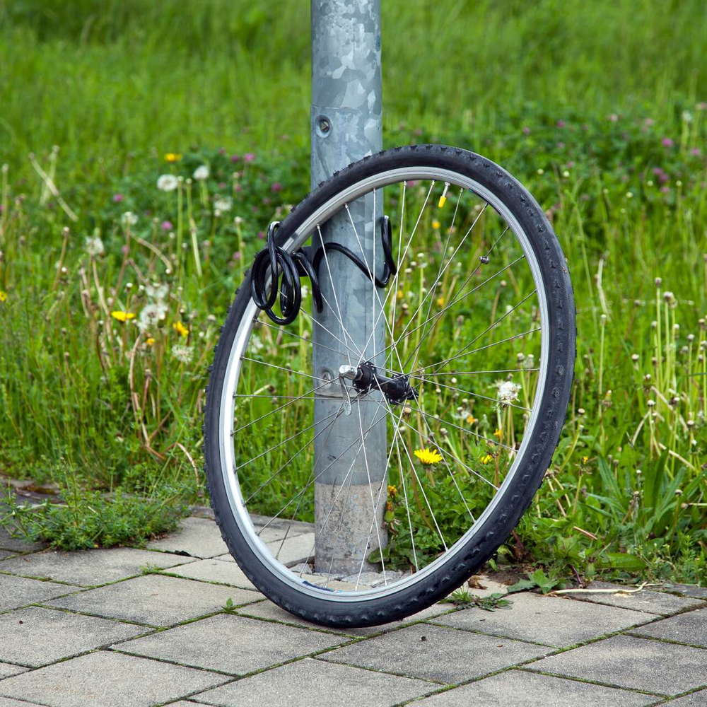 Ein Fahrradreifen ist an einer Laterne mit einer Fahrradkette angeschlossen.