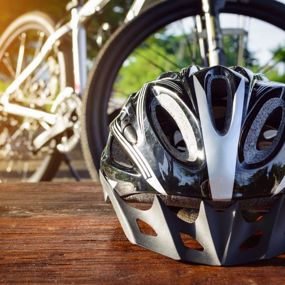 Ein Fahrradhelm liegt auf dem Tisch. Im Hintergrund befindet sich ein Mountainbike