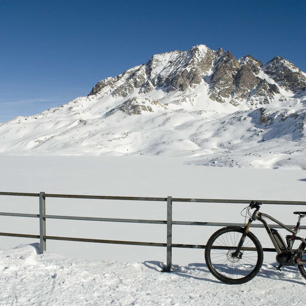 Fahrrad lehnt an inem Zaun vor wuinterlicher Bergkulisse