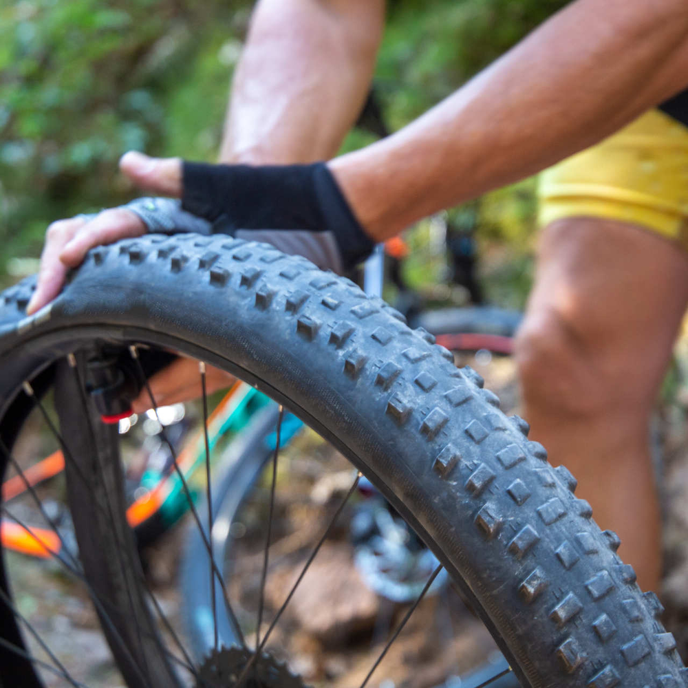 Mann prüft Druck von Fahrradschlauch mit Händen