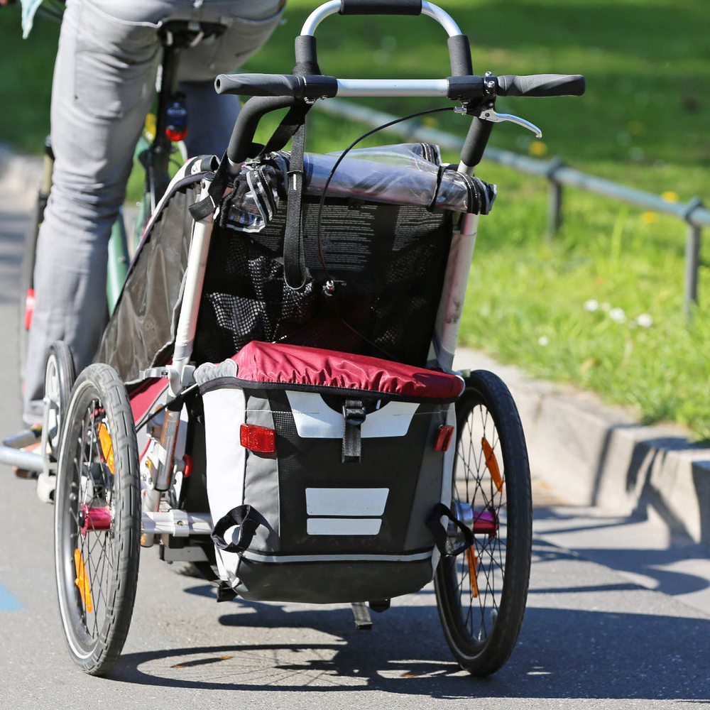 Person fährt Fahrrad mit Anhänger.