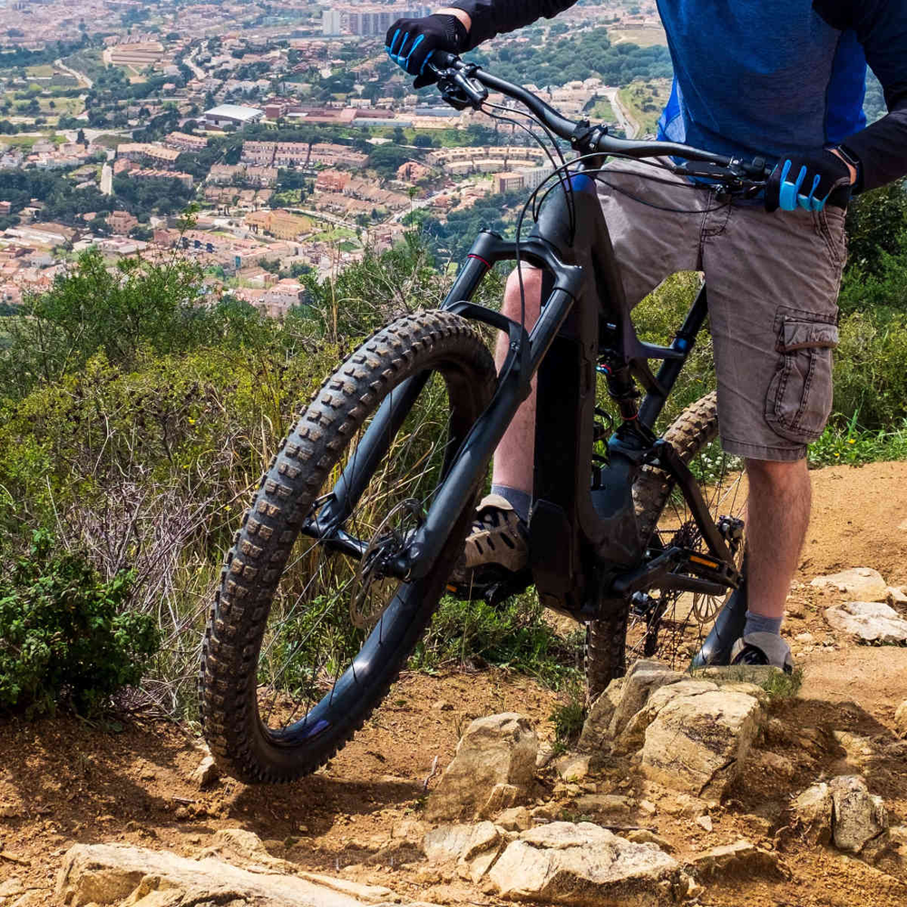 Mann fährt steilen Berg mit E-MTB hoch.