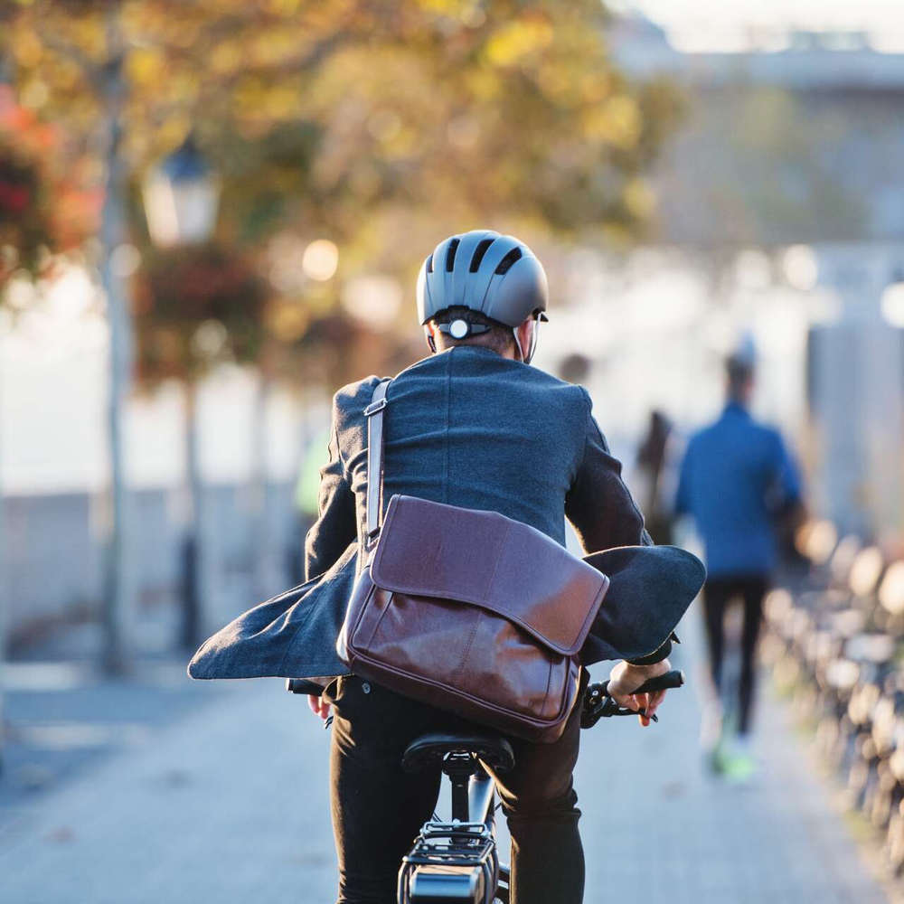 Mann in Businesskleidung fährt auf einem Fahrrad.