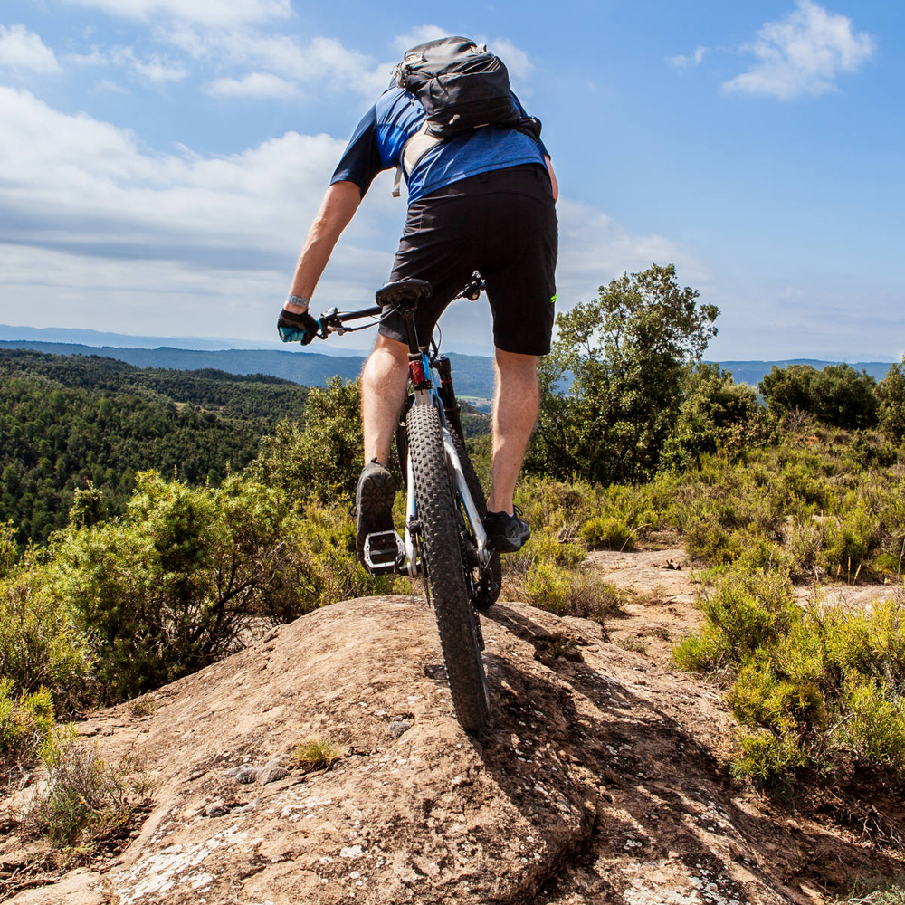 Mountainbiker fährt mit seinem Bike über einen Berggipfel