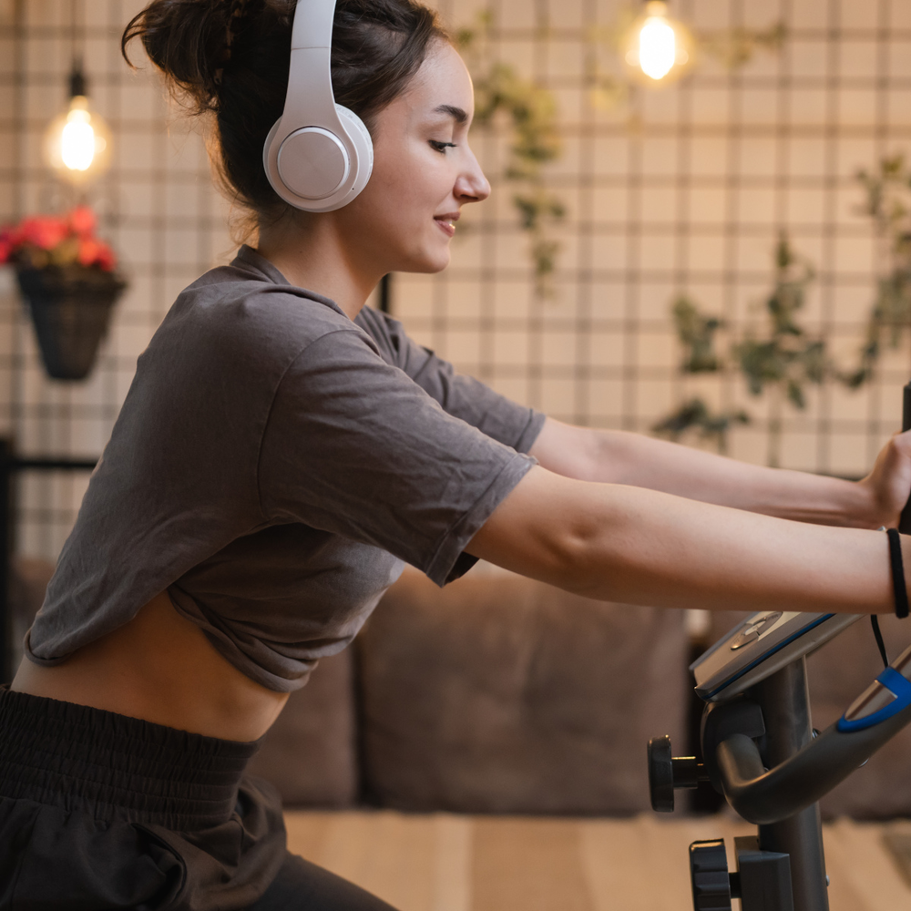 Frau fährt in der Wohnung mit einem Fahrrad-Heimtrainer