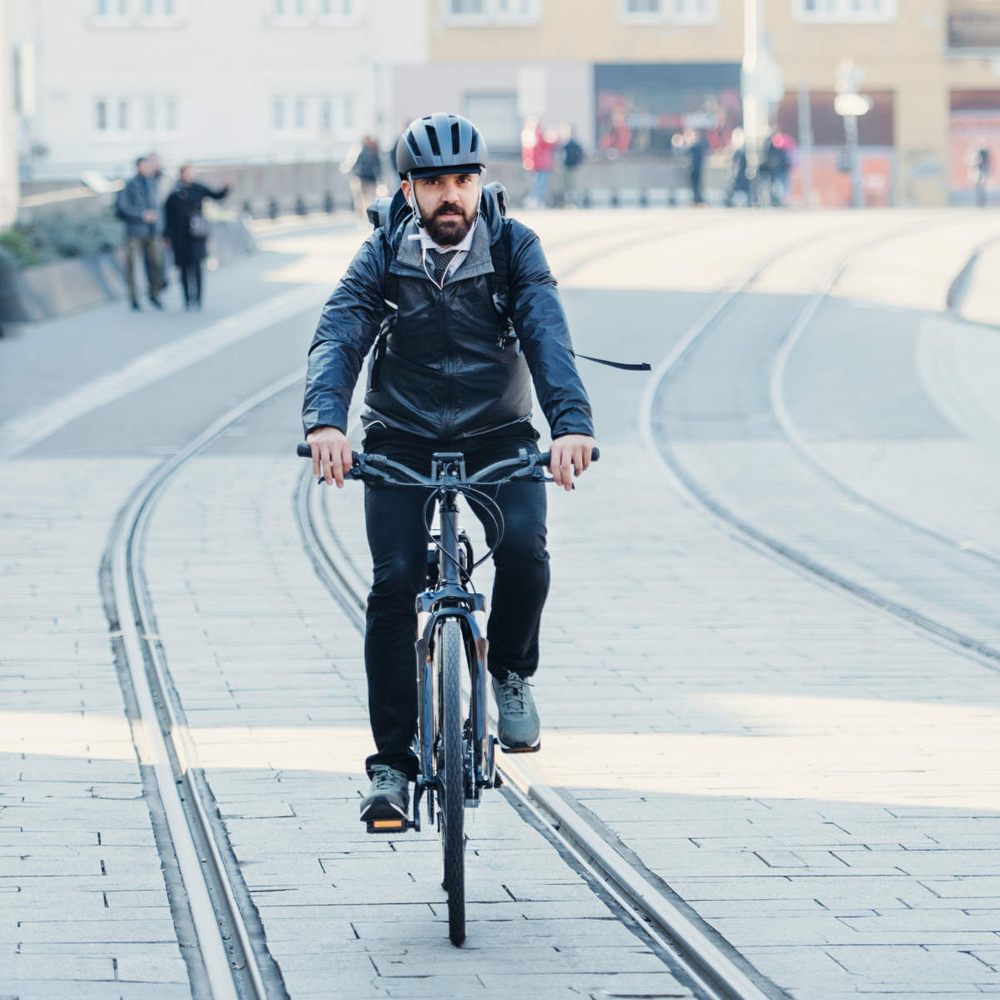 Mann mit Helm fährt durch Stadtmitte.