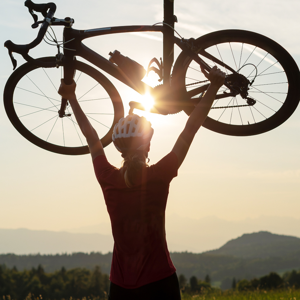 Frau hält ihr Rennrad triumphal in die Luft