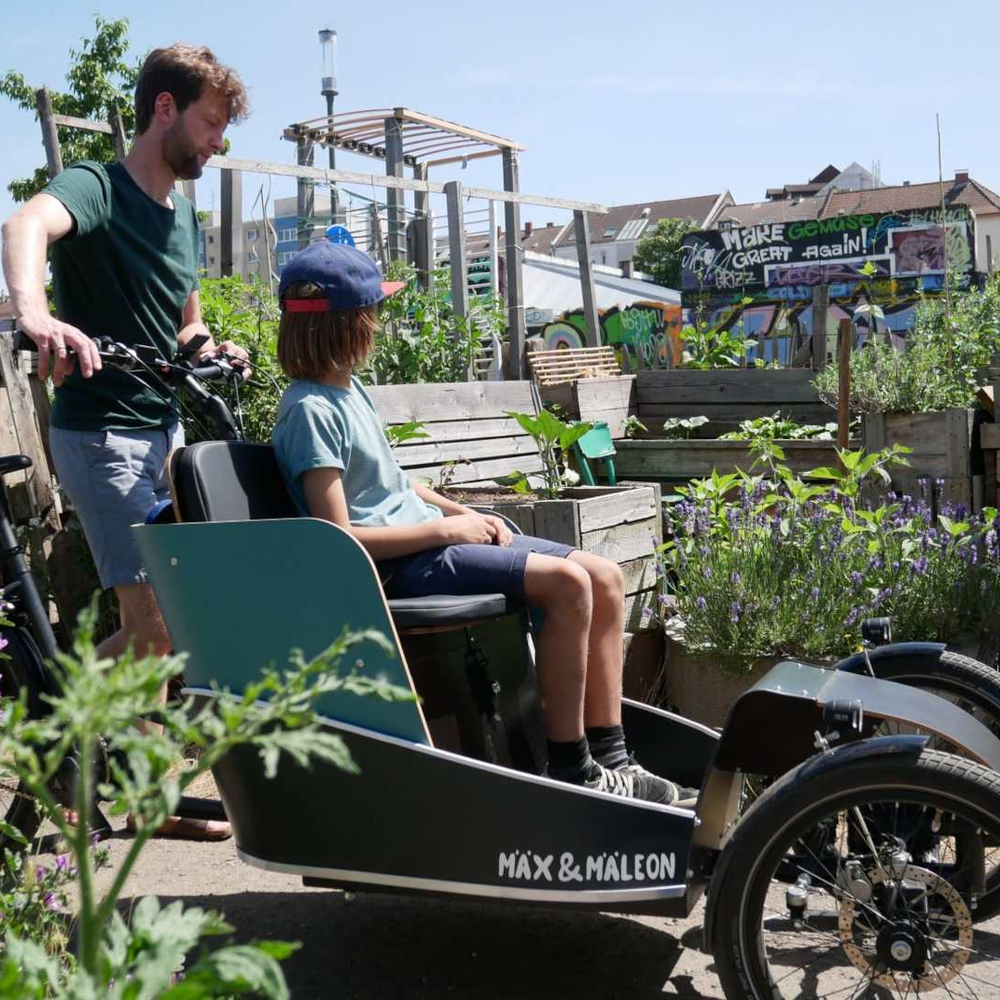 Mann mit Kind und Lastenrad in einem Feld