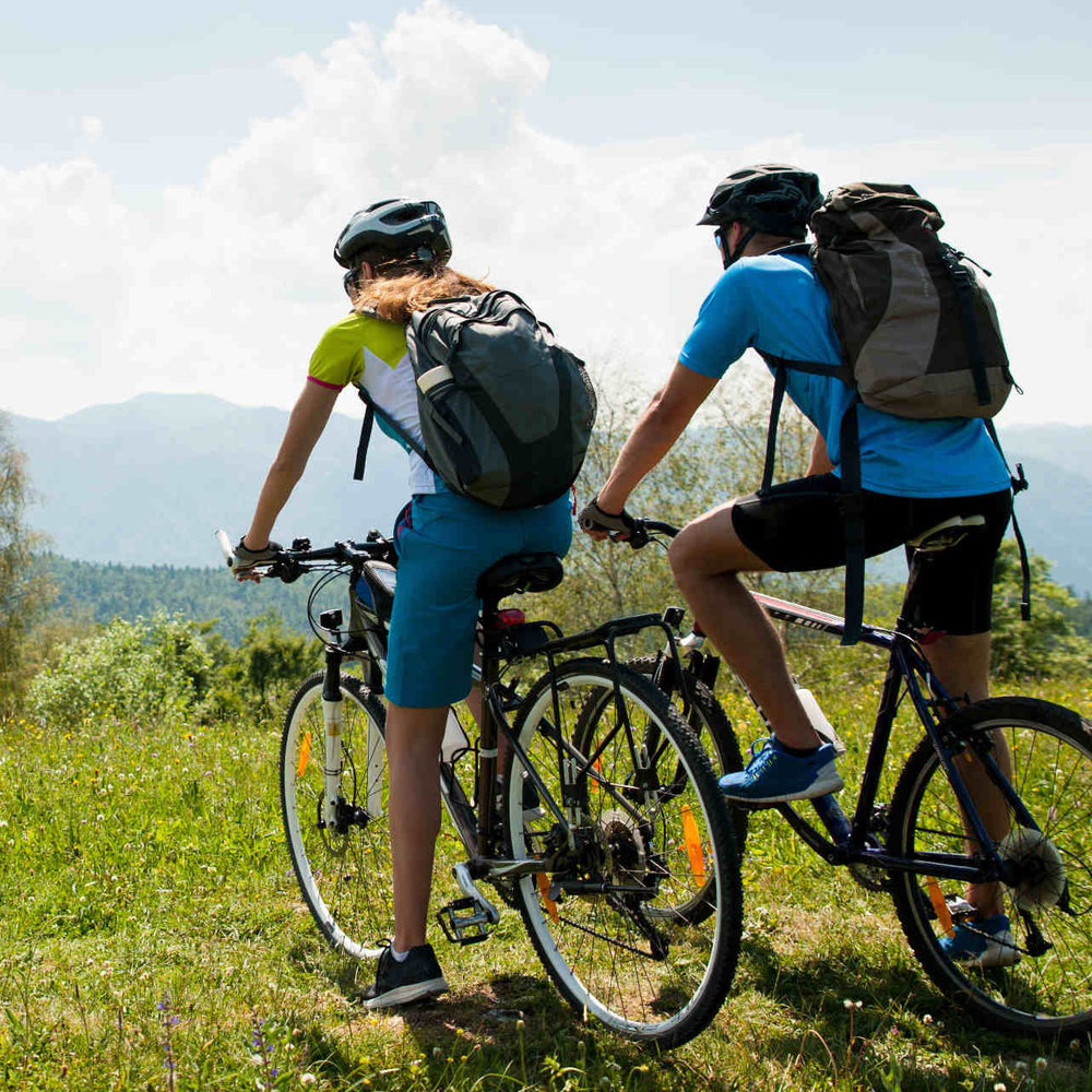 Mann und Frau auf Fahrrad schauen in Bergland.