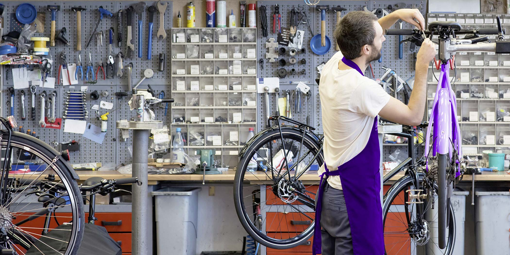 Mann repariert Fahrrad in einer Werkstatt